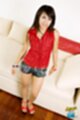 Aon standing beside couch wearing denim shorts in high heels